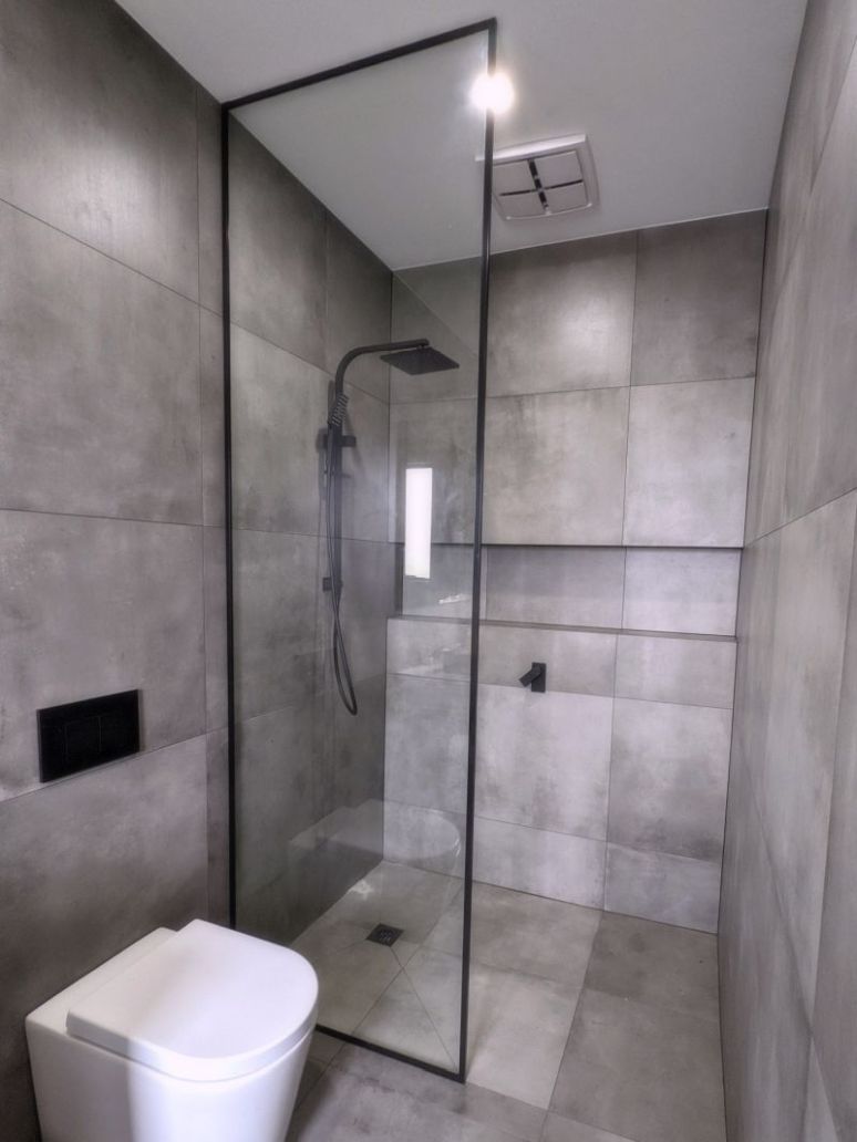Glass panel with a black frame around it in a walk in shower
