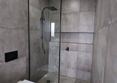 Floor to ceiling black framed shower screen