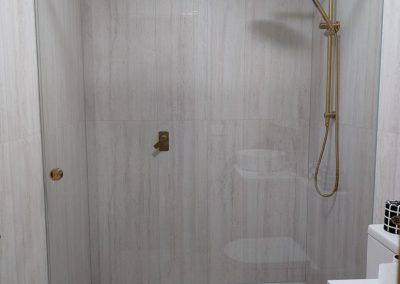 Wall-to-wall sliding shower screen with brushed gold hardware
