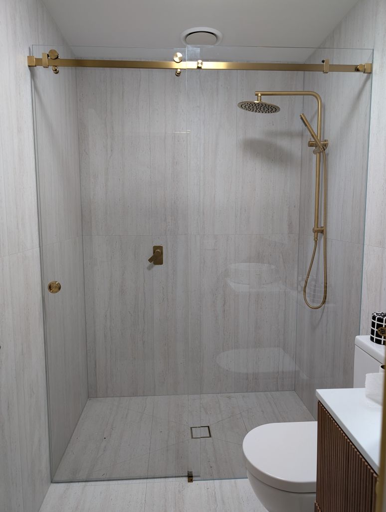 Wall-to-wall sliding shower screen with brushed gold hardware