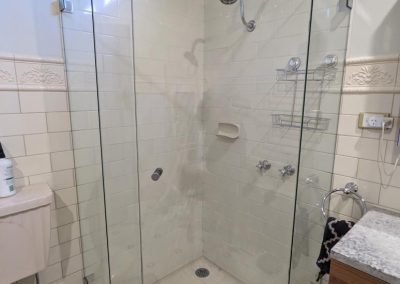 Corner frameless shower screen with clear glass and chrome fittings