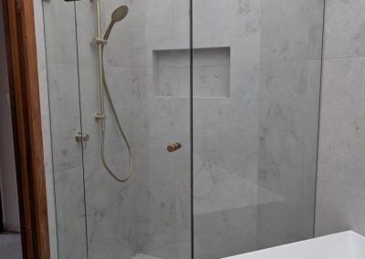 Frameless diamond shower screen with brushed brass hinges and wall niche