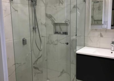 Frameless diamond shower screen with marble tiles and chrome fittings
