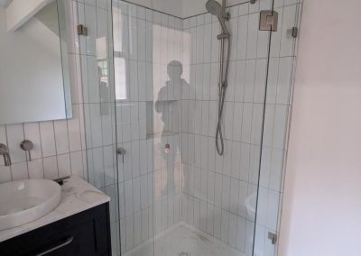Frameless diamond shower screen with white tiles and compact bathroom layout