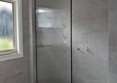 Floor to ceiling shower screen panel in a black frame