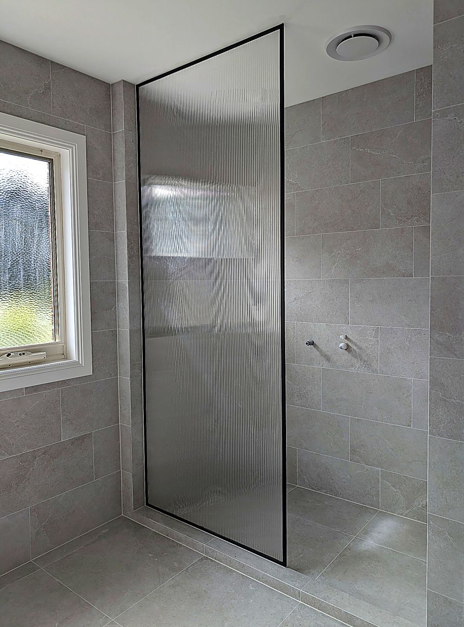 Floor to ceiling shower screen panel in a black frame
