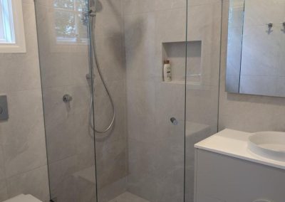 Corner diamond shower screen with chrome hinges and tiled walls