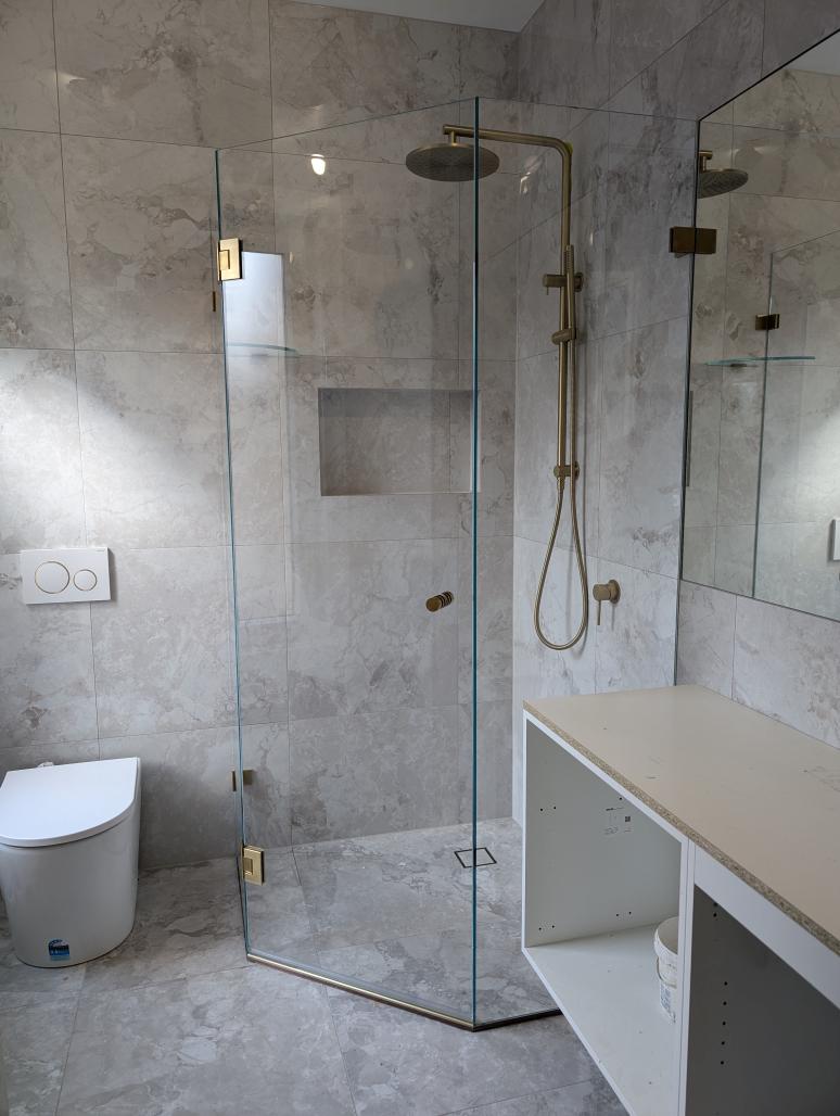 Frameless diamond shower screen with brushed brass hardware and built-in niche