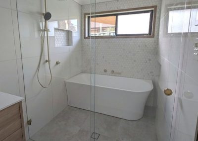 Sliding door shower screen with brushed gold hardware in a bathroom