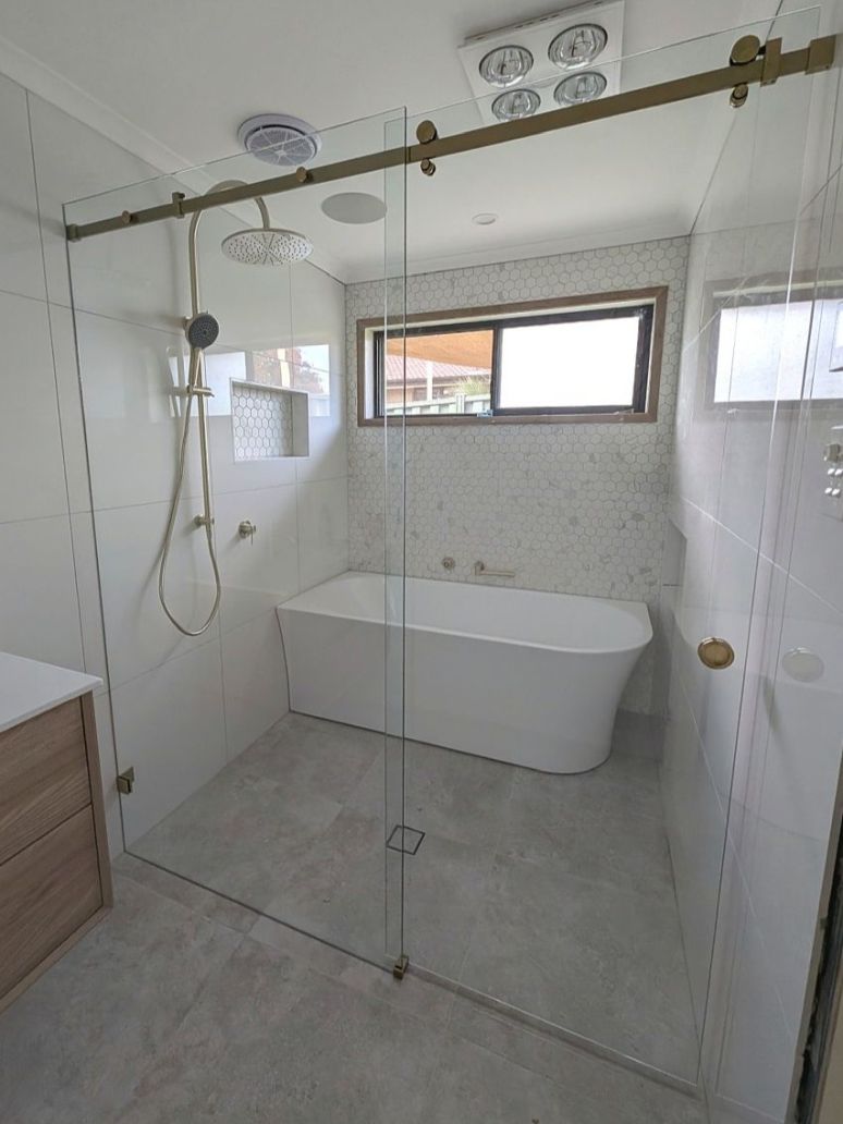 Sliding door shower screen with brushed gold hardware in a bathroom