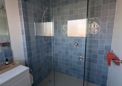 Corner frameless sliding shower screen with blue tiles