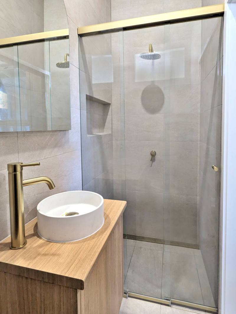 3 panel sliding shower with satin gold frame and timber vanity