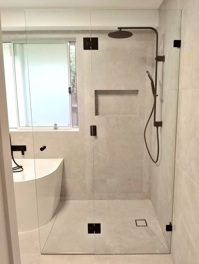 Bathroom with a beige tiles and frameless shower screen with black fittings