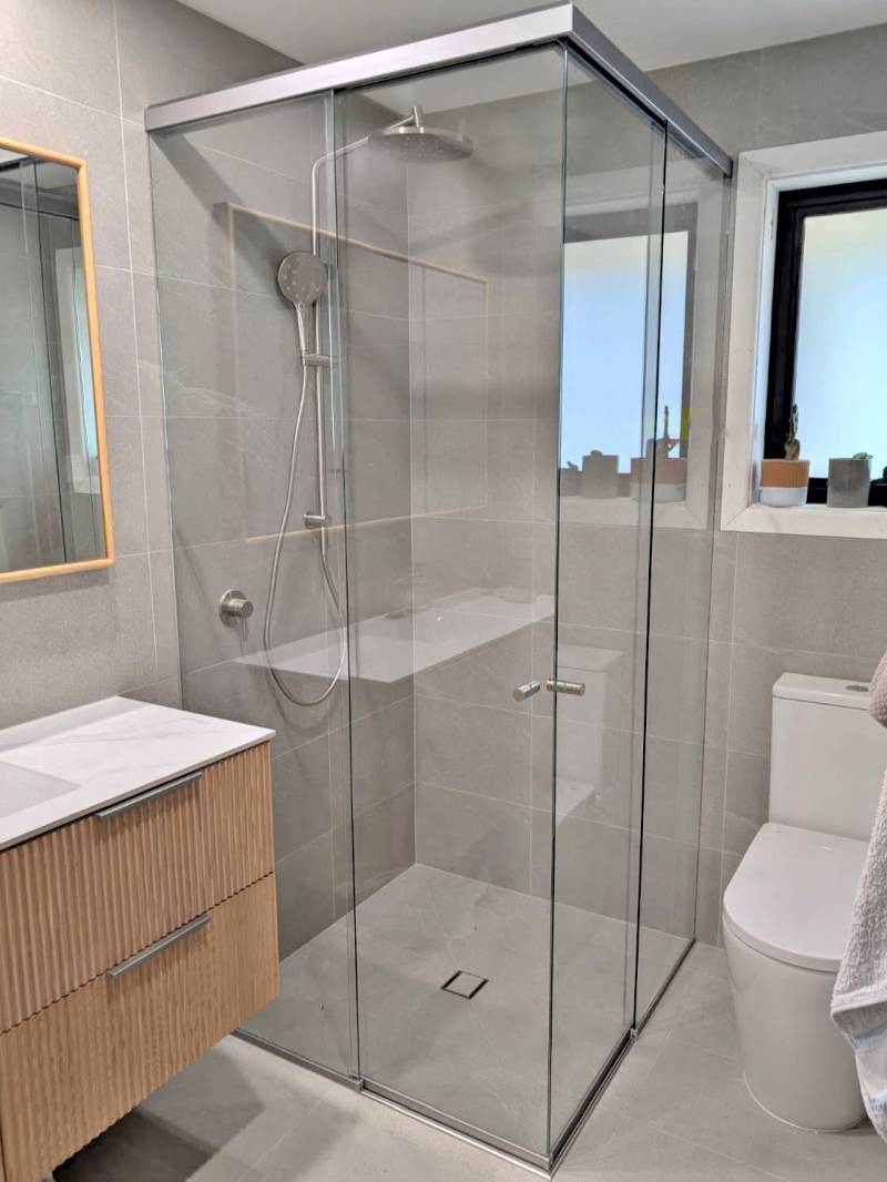 Corner-entry sliding shower screen with brushed nickel frame in a tight ensuite