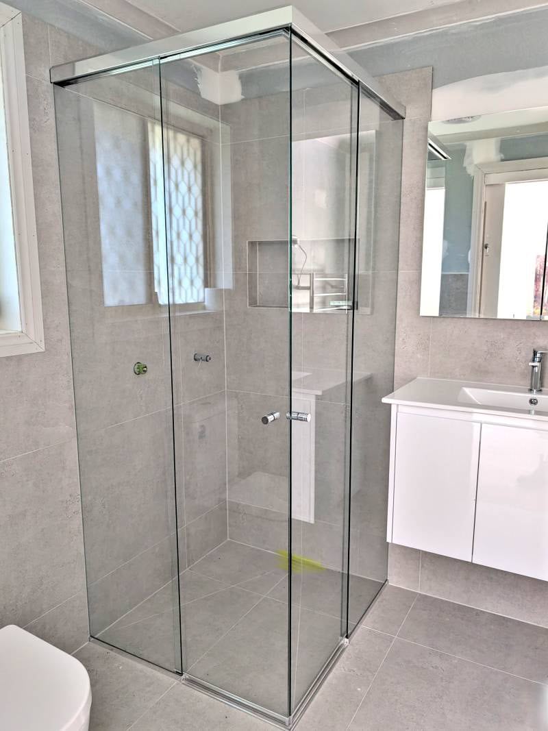 Corner-entry shower screen with chrome frame in tight batrhroom 