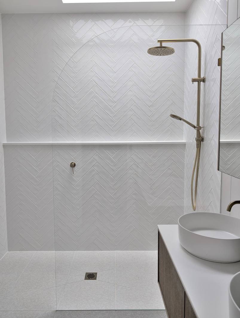 Crystal clear shower screen panel with radius corner in white bathroom with brushed gold hardware