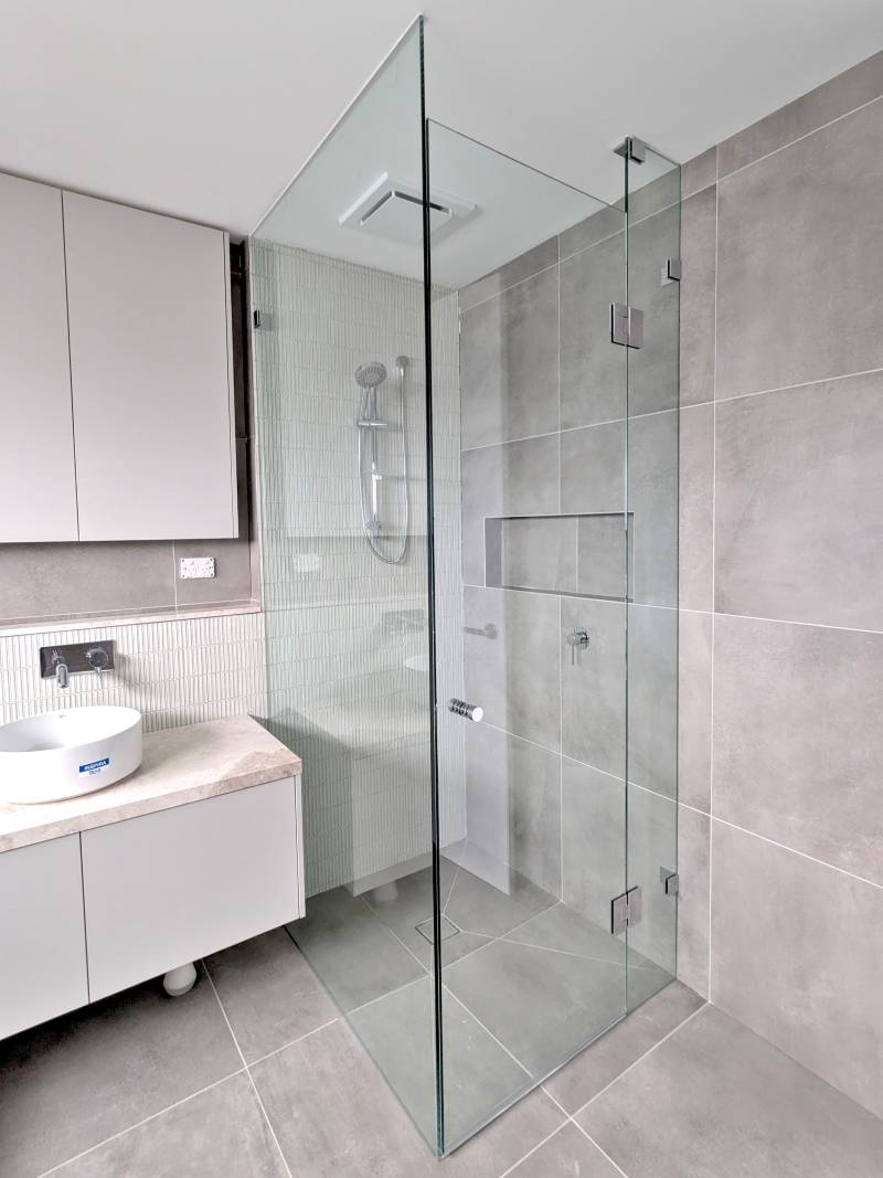 full-height-corner-shower-screen-chrome Full height frameless shower screen with large grey tiles and wall hang vanity