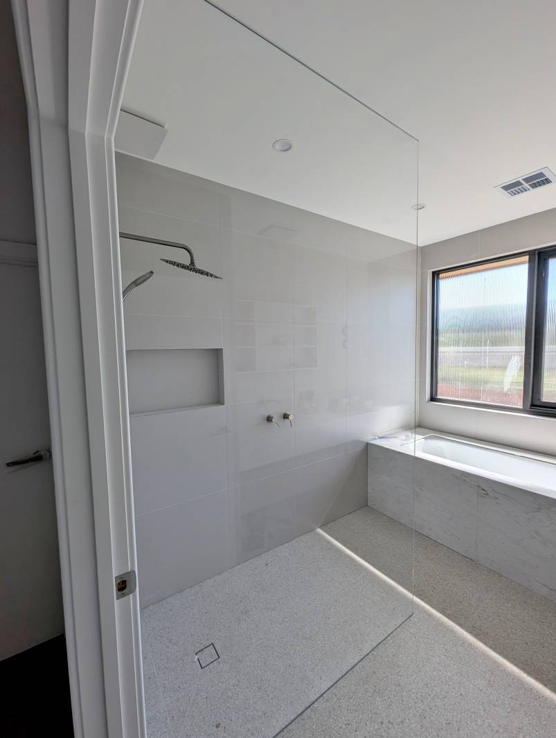 full-height-shower-screen-walk-in Large frameless shower screen panel in neutral tone bathroom