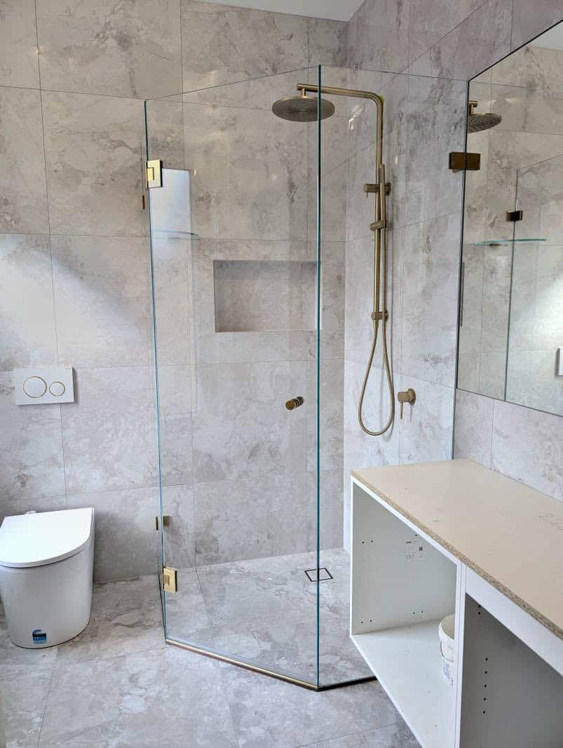 Diamond corner frameless shower screen with glass shelf and brushed gold fittings